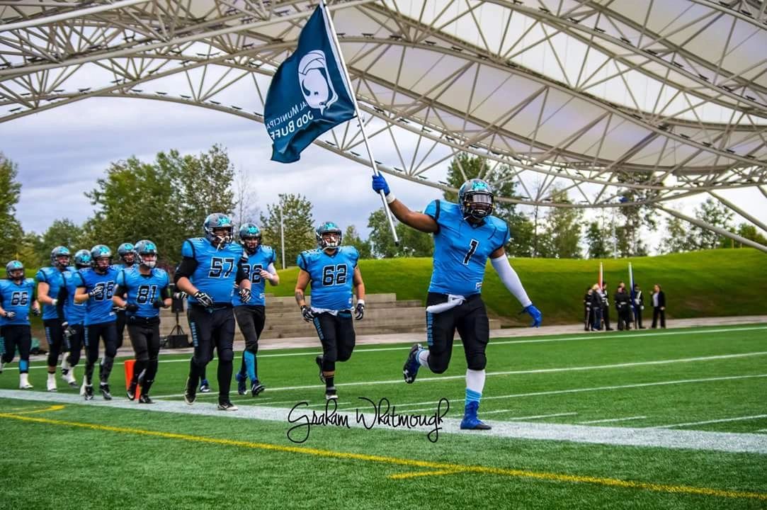 Monarchs running onto the field carrying the team flag
