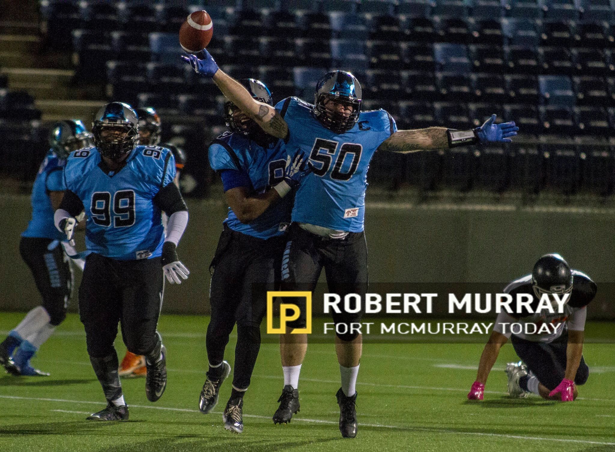 Monarchs players celebrating a big play under the lights