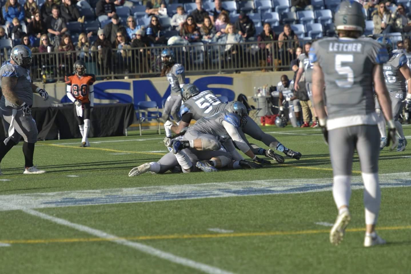 Monarchs defense making a tackle with fans in the background