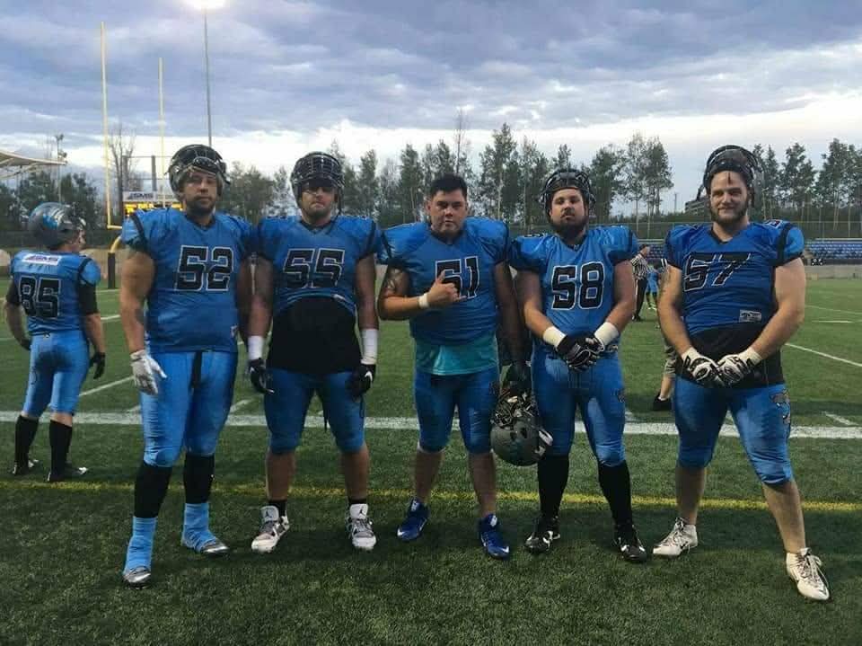 Monarchs offensive linemen in blue jerseys at SMS Equipment Stadium