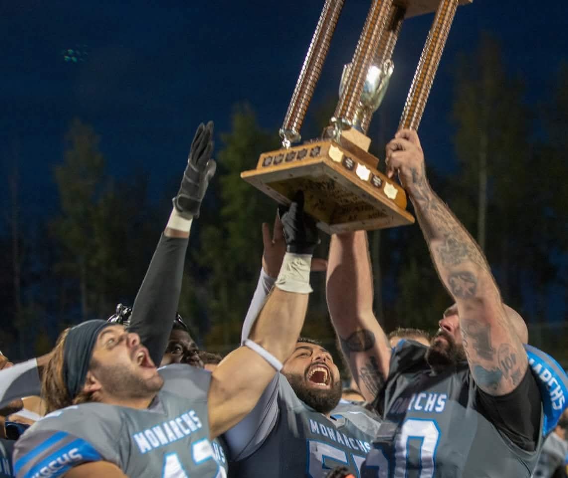 Monarchs player celebrating with championship trophy held high