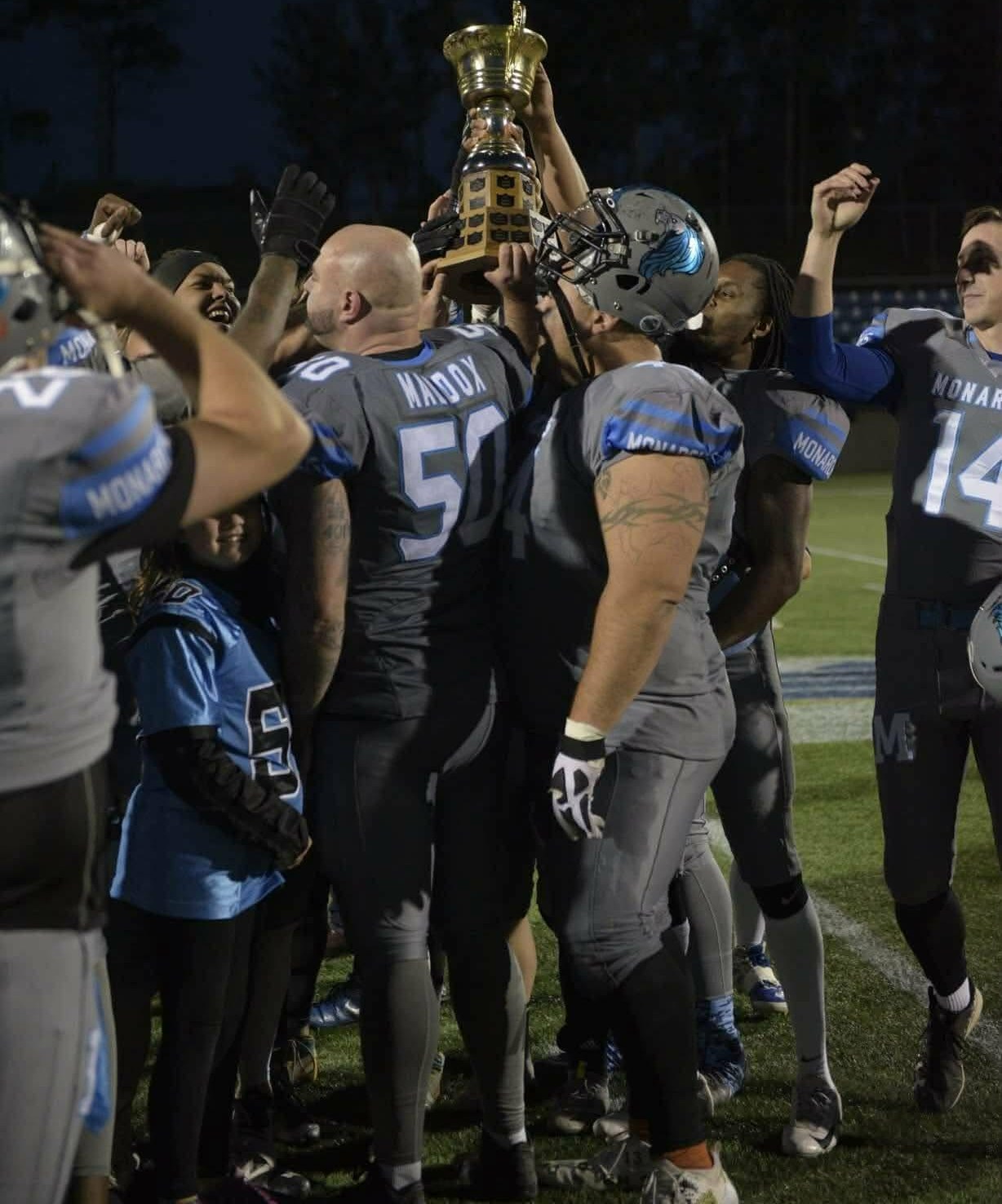 Monarchs players hoisting the championship trophy at night