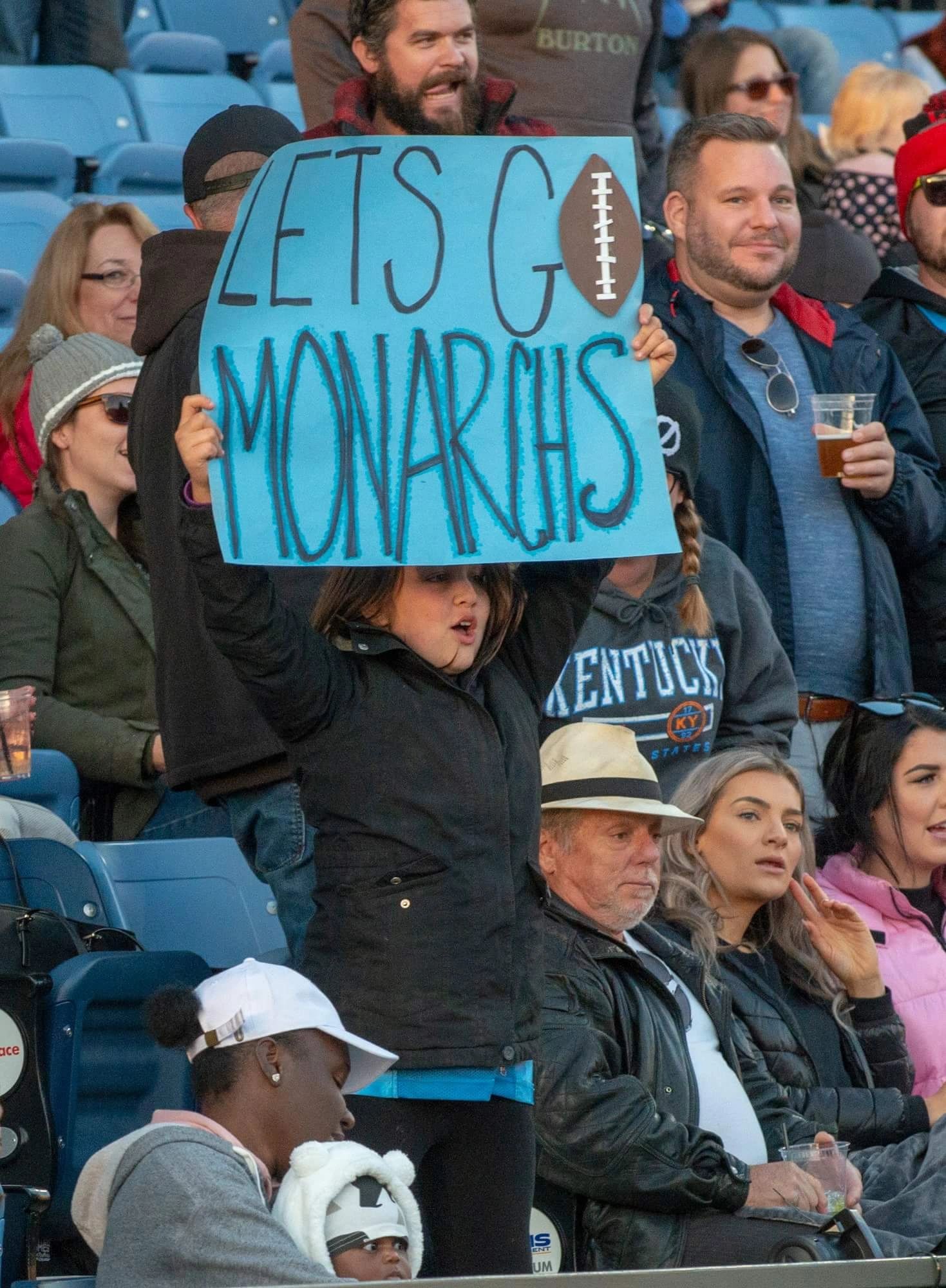 Young fan holding a Let's Go Monarchs sign in the stands